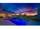 Backyard pool illuminated at dusk within screened enclosure, adjacent to covered patio at 10509 Broadland Pass, Thonotosassa, FL 33592