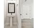 Contemporary powder room with a pedestal sink, designer mirror, and wood-look tile flooring at 10708 Oak Bend Dr, Parrish, FL 34219
