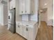 Modern kitchen showcases stainless steel refrigerator and white cabinets against stylish wood floors at 11443 Apple Tree Cir, Bradenton, FL 34211