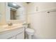 Bathroom featuring a single sink vanity, toilet, and framed mirror with an ocean-themed accent wall at 11450 Harbor Way # 5008, Largo, FL 33774