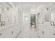 Bright, spacious bathroom with double vanities, white marble floors, white cabinetry, and gold hardware at 1220 Darlington Oak Ne Cir, St Petersburg, FL 33703