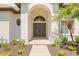 Grand front entrance with arched doorway, double doors, and lush landscaping creates inviting curb appeal at 1220 Darlington Oak Ne Cir, St Petersburg, FL 33703