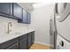 Well-equipped laundry room with blue cabinets, quartz countertop, modern fixtures, and stacked washer/dryer at 1220 Darlington Oak Ne Cir, St Petersburg, FL 33703
