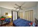 Bedroom has wood floor, ceiling fan and bed with blue sheets near desk, window and closet at 12532 115Th St, Largo, FL 33778