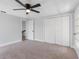 This bedroom features neutral walls, carpet, a ceiling fan, and a closet for ample storage space at 15307 Summerwind Dr, Tampa, FL 33624