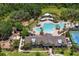 Aerial view of the community pool, clubhouse, playground, and tennis court surrounded by lush greenery and palm trees at 19204 Briarbrook Dr, Tampa, FL 33647