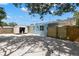View of the light blue house exterior, sheds, and fenced-in area in the stone-covered backyard at 1974 N Betty Ln, Clearwater, FL 33755