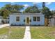 Charming light blue home featuring a freshly landscaped front yard and vibrant yellow front door at 1974 N Betty Ln, Clearwater, FL 33755