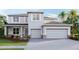 Modern two-story home boasts a three-car garage, manicured lawn, and contemporary architectural details at 2250 Rikkola Ln, Wesley Chapel, FL 33543