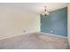 Dining room featuring neutral carpet, a blue accent wall, and a charming chandelier at 2310 Denmark St # 30, Clearwater, FL 33763