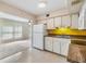 Functional kitchen with white appliances and cabinets, a view into a sunlit living area, and neutral flooring at 2310 Denmark St # 30, Clearwater, FL 33763