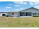 The backyard shows green grass, a white house with white gravel, screened lanai, and partial view of garage at 2313 Grenoble Pl # 2313, Sun City Center, FL 33573