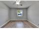 Bedroom featuring wood-look floors, neutral grey walls, a ceiling fan, and a window at 2313 Grenoble Pl # 2313, Sun City Center, FL 33573