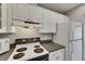 Appliance view showcasing the range and refrigerator with white cabinetry and black countertops at 2313 Grenoble Pl # 2313, Sun City Center, FL 33573