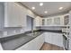 Well-lit kitchen featuring white cabinets, dark countertops, and stainless steel sink at 2313 Grenoble Pl # 2313, Sun City Center, FL 33573