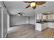Open-concept living room with kitchen view, hardwood floors, ceiling fans, and natural light at 2313 Grenoble Pl # 2313, Sun City Center, FL 33573