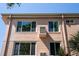 A close exterior shot of a peach-colored home with palm trees and large windows in bright, natural lighting at 2458 Columbia Dr E # 84, Clearwater, FL 33763