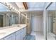 Bright bathroom with a double sink vanity, a large mirror with lights, and a glass-enclosed shower at 2663 Sequoia Ter # 2663, Palm Harbor, FL 34683