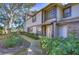 Inviting townhome featuring lush landscaping, tan siding, and brick accents at 2663 Sequoia Ter # 2663, Palm Harbor, FL 34683