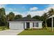 Charming single-story home with a gray facade, attached garage, and well-manicured lawn and landscaping at 3061 Pink Gerbera Sq, Plant City, FL 33566