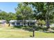 An eye-level view of a one story house, with green grass and well-established landscaping and an American flag at 315 Oakwood Blvd, Oldsmar, FL 34677