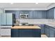The kitchen features blue cabinets, stainless steel appliances, a marble backsplash, and a wood-topped island at 315 Oakwood Blvd, Oldsmar, FL 34677