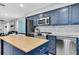 Kitchen featuring stainless steel appliances, blue cabinets with bronze hardware, an island, and marble backsplash at 315 Oakwood Blvd, Oldsmar, FL 34677