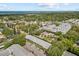 Aerial view of neighborhood with mature trees, houses, and ocean in the distance at 500 Glennes Ln # 205, Dunedin, FL 34698