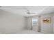 This bedroom has neutral walls, a ceiling fan, white tile flooring, and a window with natural light at 500 Glennes Ln # 205, Dunedin, FL 34698