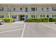 Two-story condo building with blue shutters, landscaping, and assigned parking at 500 Glennes Ln # 205, Dunedin, FL 34698