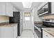 Galley kitchen featuring granite countertops and white cabinets and a stainless steel refrigerator and oven at 500 Glennes Ln # 205, Dunedin, FL 34698