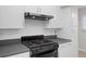 Well-maintained kitchen with white cabinets, black appliances, and stainless steel range hood at 5980 Shore S Blvd # 312, Gulfport, FL 33707