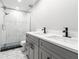 Bathroom featuring double sinks, a glass shower with decorative tile, updated toilet and gray vanity at 6070 Denver Ne St, St Petersburg, FL 33703
