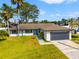 Charming single-story home with a two-car garage, blue front door, and beautifully landscaped front yard at 6070 Denver Ne St, St Petersburg, FL 33703