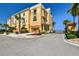 Stunning yellow townhome with a red tile roof, lush tropical landscaping, and a secure gated entrance at 6412 Mayra Shores Ln, Apollo Beach, FL 33572