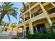 Stunning condo building with multiple balconies and a beautiful yellow facade, accented by lush landscaping at 6412 Mayra Shores Ln, Apollo Beach, FL 33572