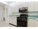 Well-lit kitchen features white cabinets, black appliances, and tile flooring at 646 Allegheny Dr, Sun City Center, FL 33573