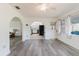 Bright living area with gray wood-look floors, arched doorways, and views of the kitchen at 646 Allegheny Dr, Sun City Center, FL 33573