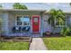 Charming home featuring a red front door, brick facade, and a cozy seating area on the porch at 7000 14Th N St, St Petersburg, FL 33702