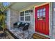 Inviting front porch with brick flooring, a vibrant red door, and cozy seating perfect for relaxing at 7000 14Th N St, St Petersburg, FL 33702