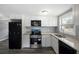 Bright kitchen features white cabinets, granite counters, and modern black appliances at 8624 N Semmes St, Tampa, FL 33604