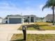 Charming single-story home with a well-manicured lawn, gray exterior, and two-car garage at 8702 Pinafore Dr, New Port Richey, FL 34653