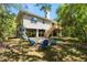 Unique raised home with backyard firepit area and seating, surrounded by lush greenery at 9019 Stone Dr, Webster, FL 33597