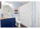 Well-lit bathroom features navy vanity, elegant gold mirror, and white shower curtain at 9019 Stone Dr, Webster, FL 33597