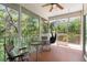 Relaxing screened porch with ceiling fan, hammock chair, and outdoor seating overlooking the trees at 9019 Stone Dr, Webster, FL 33597