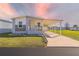 Inviting single-story home with a covered carport and a well-manicured lawn with beautiful sunset at 10029 Wellington Ave, Dade City, FL 33525