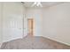 Spacious bedroom featuring neutral carpeting, a white ceiling fan and open doorway to ensuite bathroom at 10135 Post Harvest Dr, Riverview, FL 33578