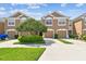 Inviting two-story townhome featuring a two-car garage, manicured lawn, and lush shrubbery at 10135 Post Harvest Dr, Riverview, FL 33578