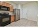 Efficient kitchen with black appliances, wood cabinets, and a stainless steel refrigerator at 10135 Post Harvest Dr, Riverview, FL 33578