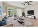 Bright living room featuring a ceiling fan, large windows, and comfortable seating area at 10135 Post Harvest Dr, Riverview, FL 33578